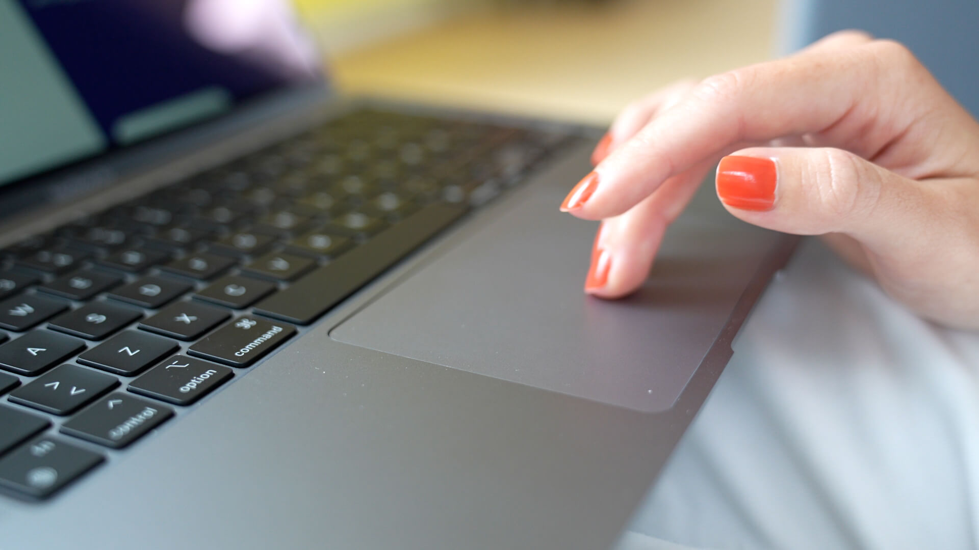 Kvinde med laptop, med fingre på touchpad