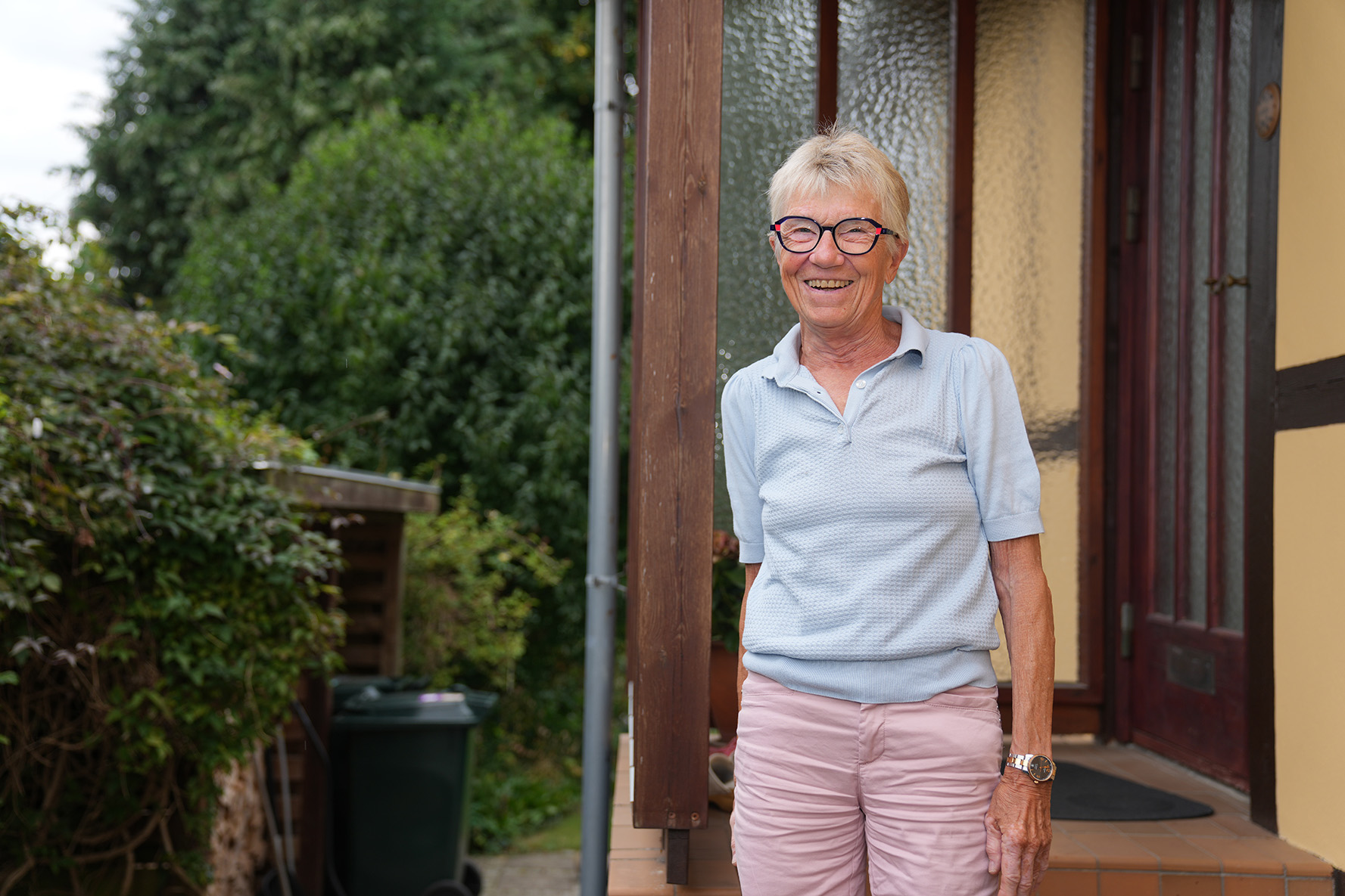 En smilende Anne Marie Kofod på trappen ved sit hus